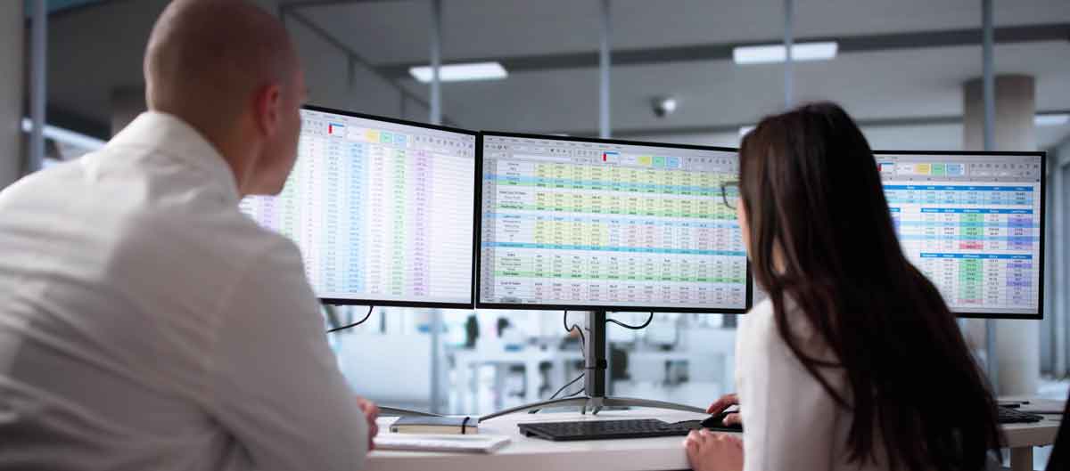 Business people looking at three separate spreadsheets